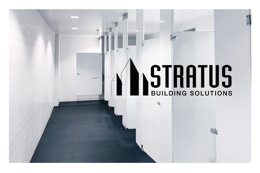 Clean office bathroom with clean white walls and stall doors and the Stratus logo in black